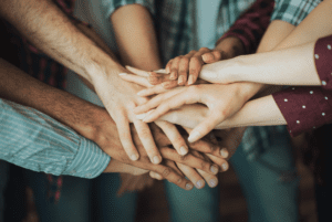 Many hands of different skin colours overlapping. 