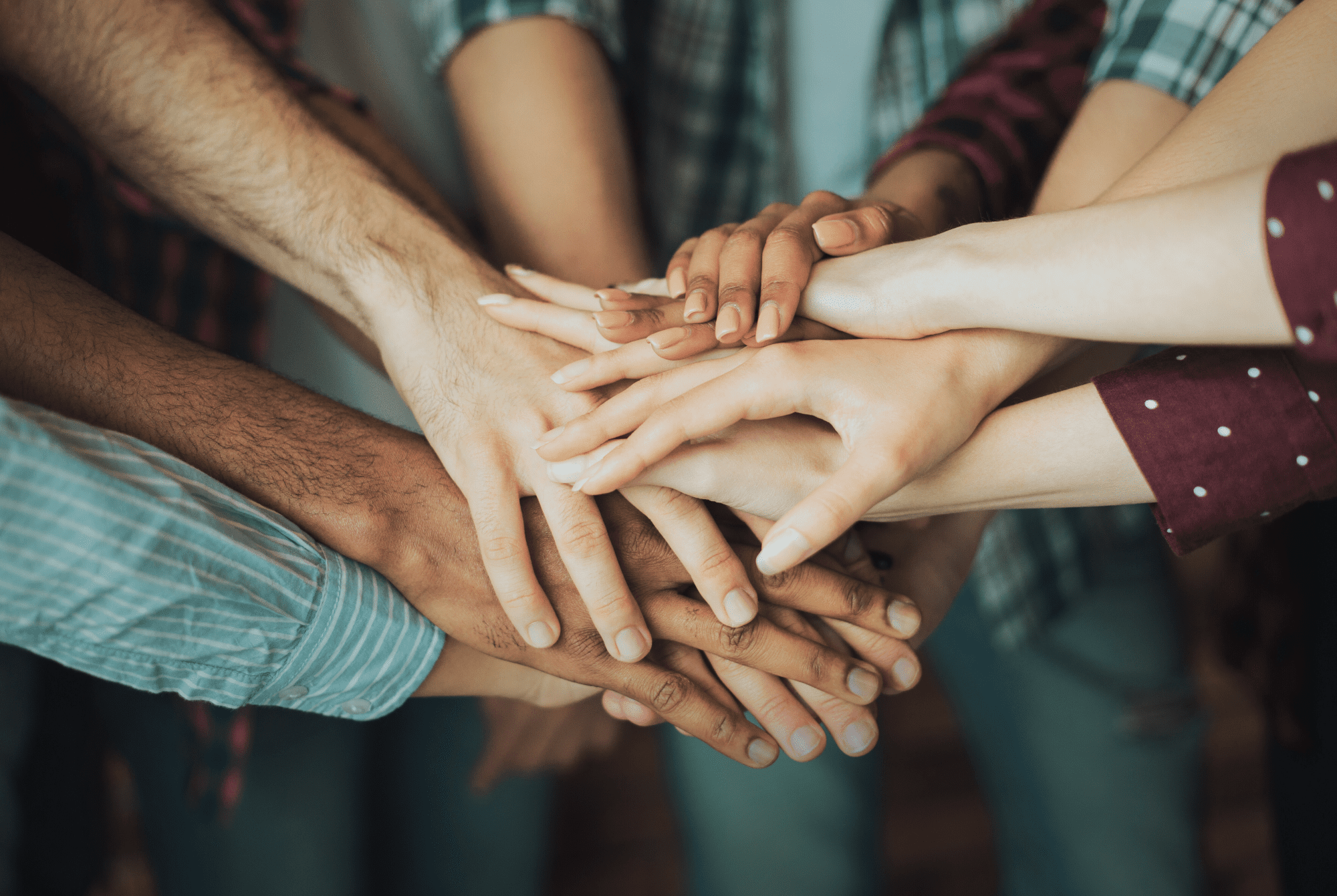 Many hands of different skin colours overlapping. 